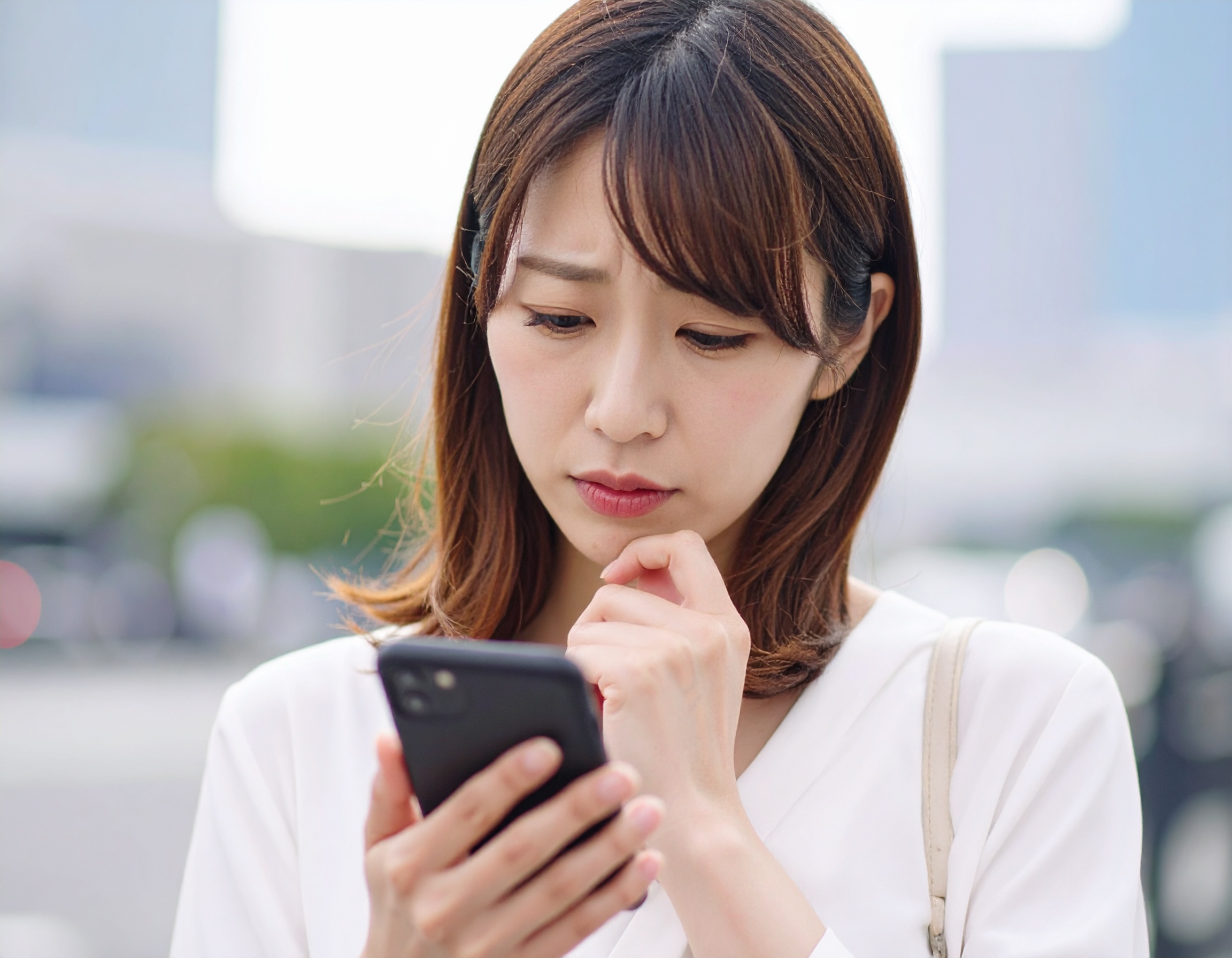 スマホを見つめて悩む女性