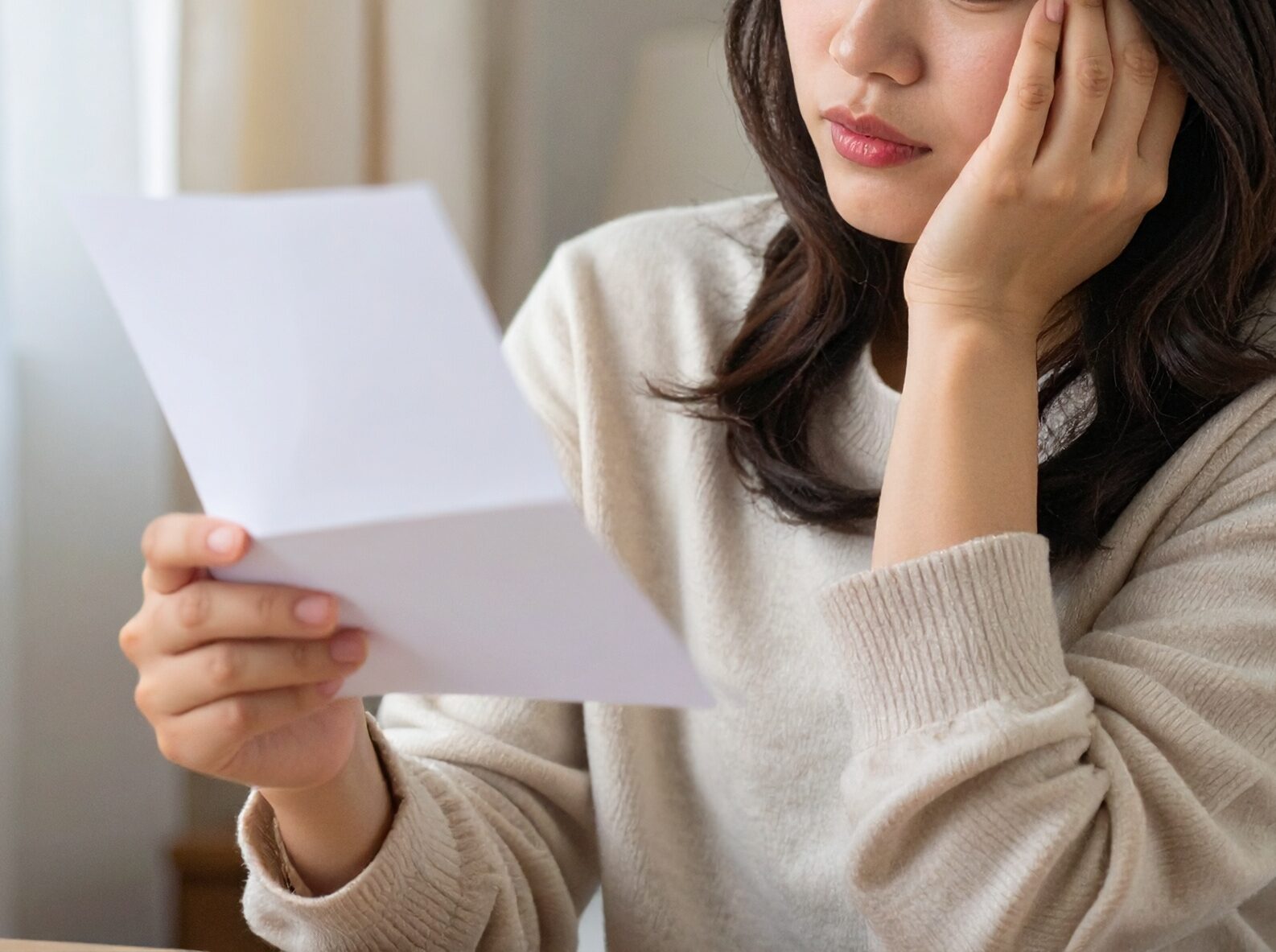 手紙を見て悩む女性